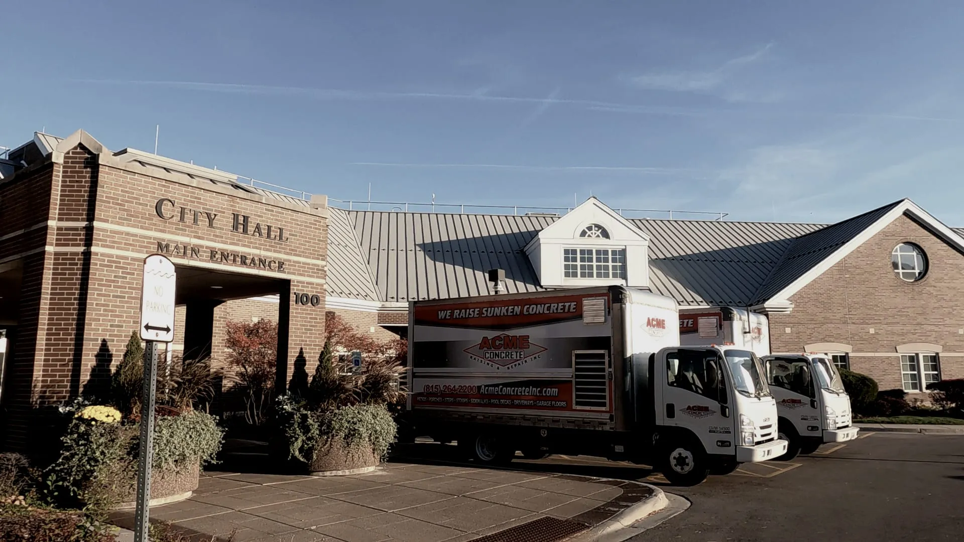 Acme Concrete box trucks parked outside a city hall main entrance