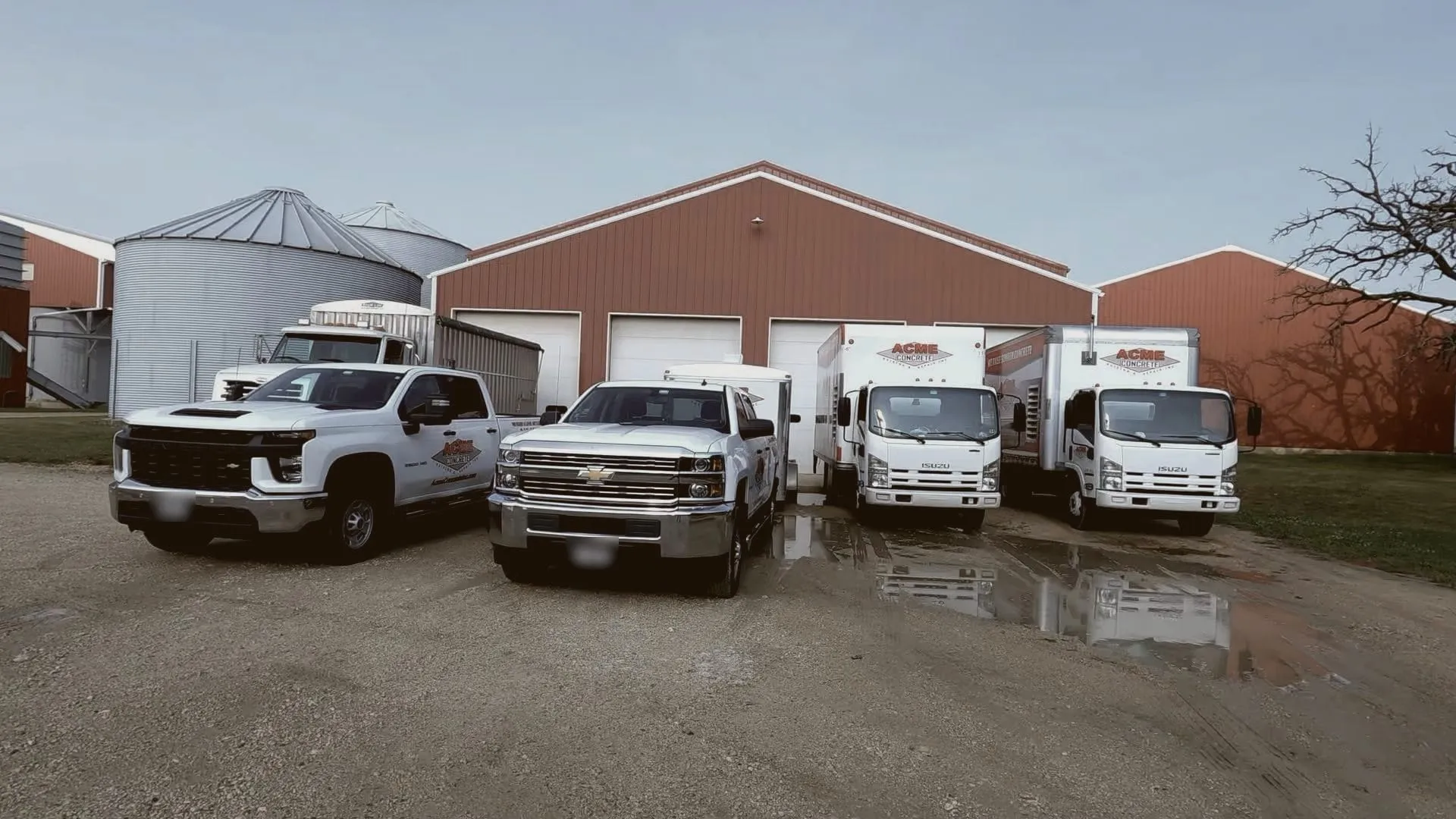The Acme fleet of pickups and box trucks lined up outside a red barn