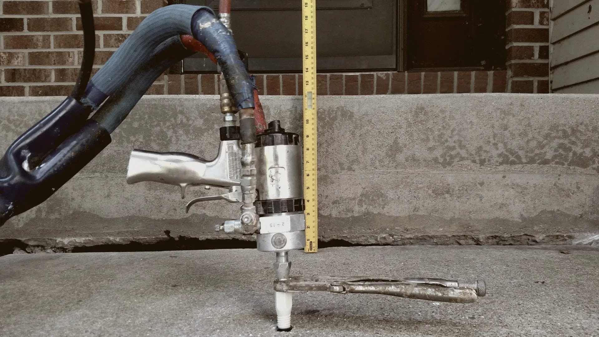 Injection gun on a port at a front step, a tape measure against the gap