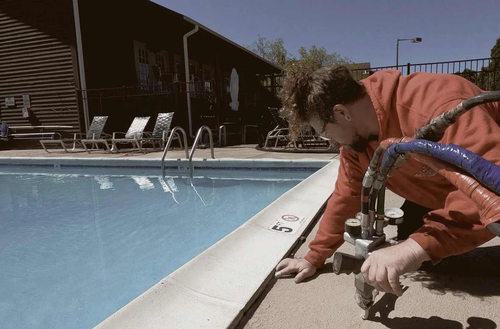 Crew member injecting a pool deck beside the coping