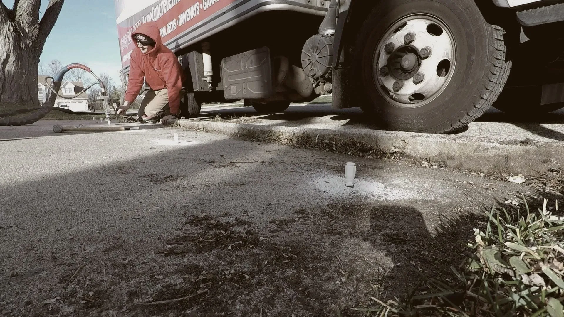 Injection ports set in a sidewalk beside an Acme box truck, crew member at work