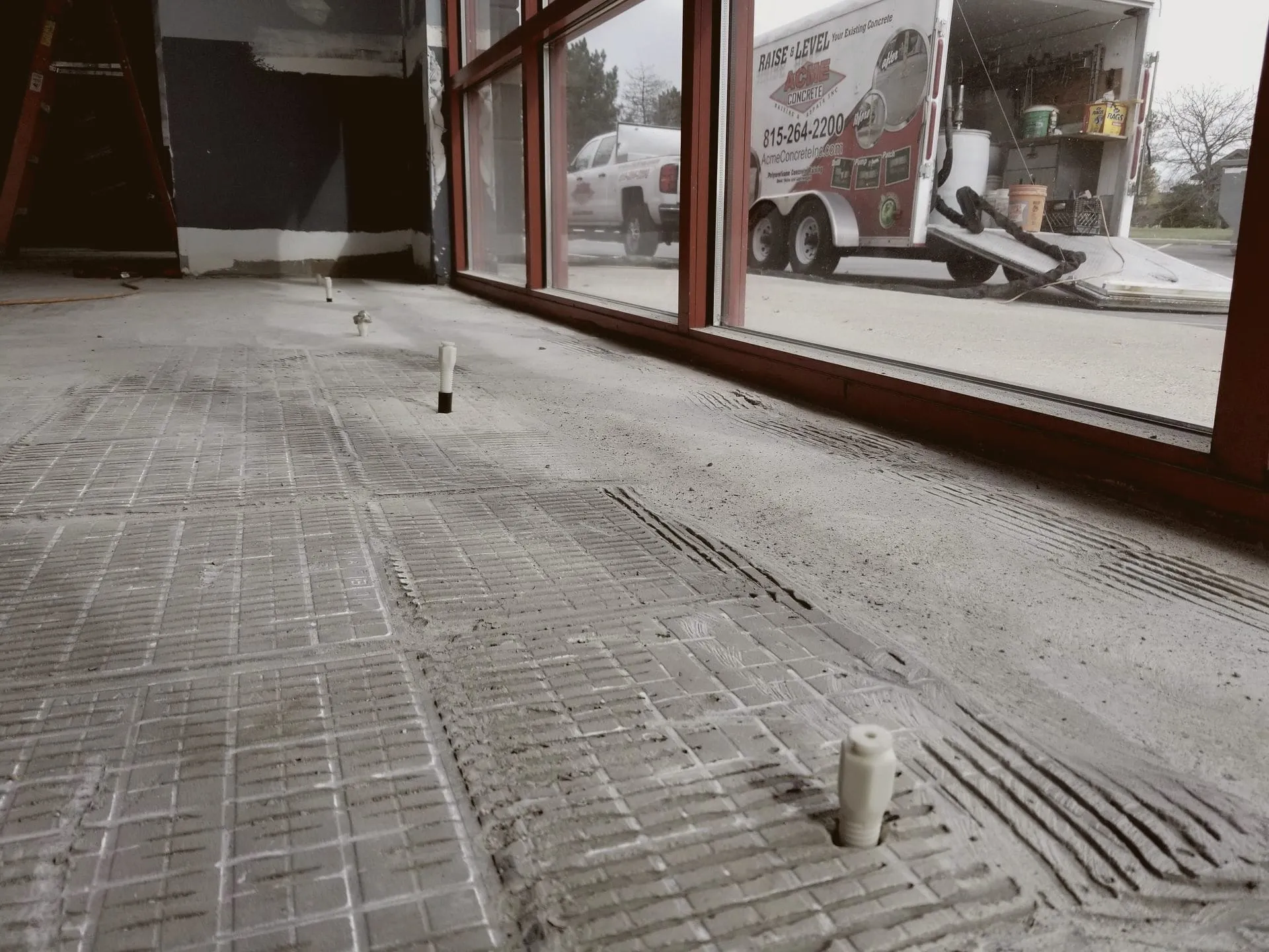 Ports set in a stripped storefront floor, the Acme trailer outside the window