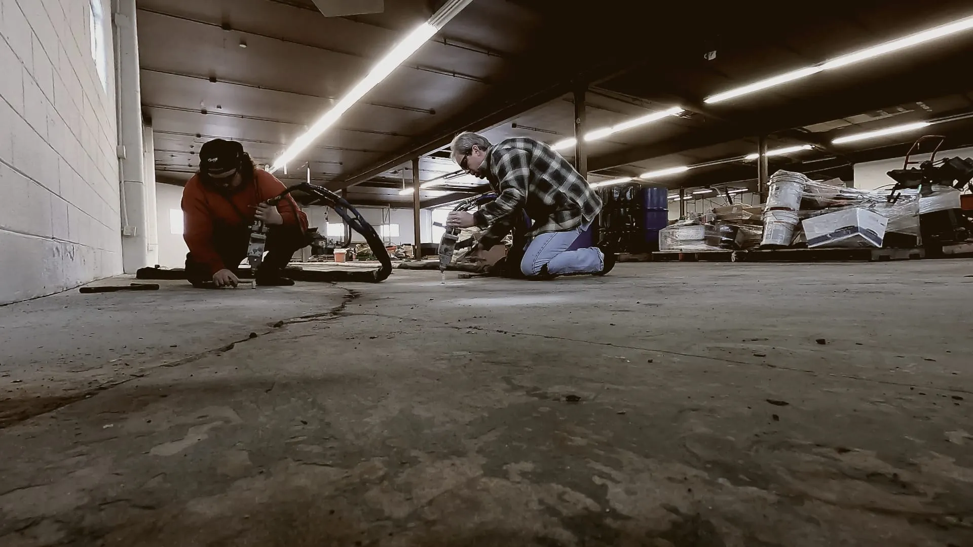 Two crew members injecting a cracked warehouse floor